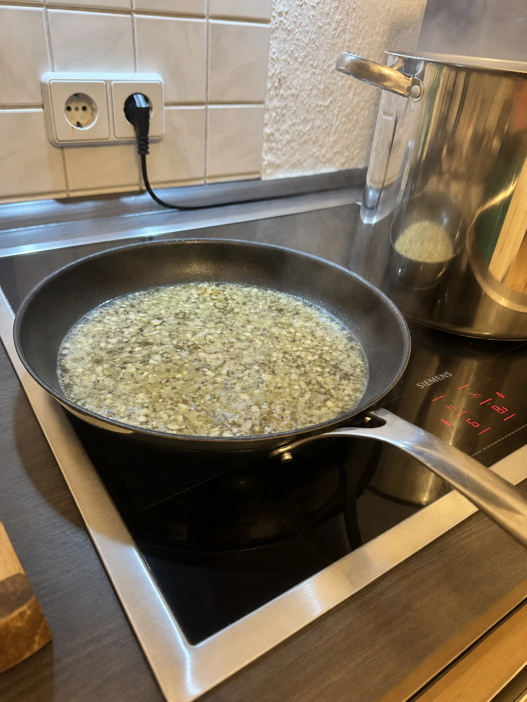 Fein gehackte Zwiebel und Knoblauch reduzieren mit Weißwein in der Pfanne